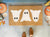 Ghost Trio Halloween Doormat on a front porch decorated with pumpkins.